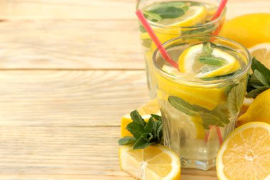 Doğal ahşap arka plan üzerinde plastik bardak nane ve limon ile ev yapımı limonata. Ferahlatıcı limonata içeceği.