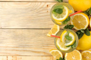 Doğal ahşap arka plan üzerinde plastik bardak nane ve limon ile ev yapımı limonata. Ferahlatıcı limonata içeceği. üst görünüm