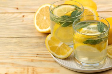 Doğal ahşap arka plan üzerinde plastik bardak nane ve limon ile ev yapımı limonata. Ferahlatıcı limonata içeceği.
