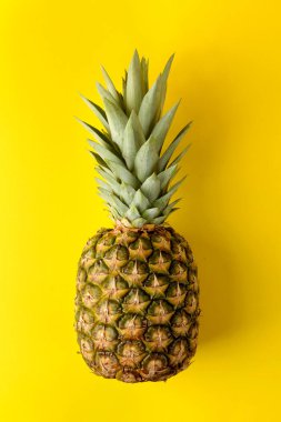 Parlak sarı bir arka plan üzerinde büyük olgun meyve ananas. Yaz. üst görünüm.