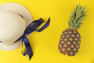 Parlak sarı bir arka plan üzerinde büyük olgun meyve ananas ve yaz şapka. Yaz. üst görünüm.