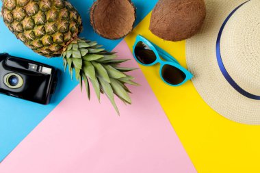 Parlak sarı, mavi ve pembe arka planda büyük olgun ananas meyve ve yaz aksesuarları. Yaz. üst görünüm.