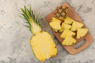 Büyük olgun meyve ananas. Hafif beton arka plan üzerinde bir kesme tahtası üzerinde ananas dilimleri. Yaz. üst görünüm.