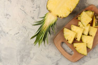 Büyük olgun meyve ananas. Hafif beton arka plan üzerinde bir kesme tahtası üzerinde ananas dilimleri. Yaz. üst görünüm.