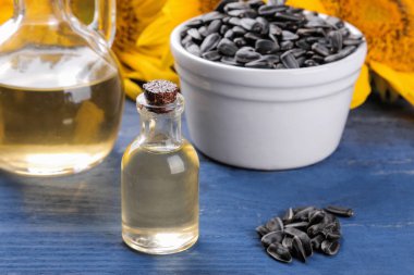 mavi ahşap arka plan üzerinde arka planda güzel sarı ayçiçeği ile ayçiçeği tohumu yağı ve Ayçiçeği tohumları