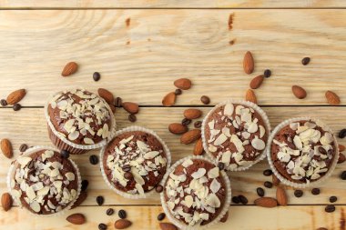 Lezzetli, tatlı çikolatalı kekler, doğal bir ahşap masada badem fındık yanında badem yaprakları ile. üst görünüm