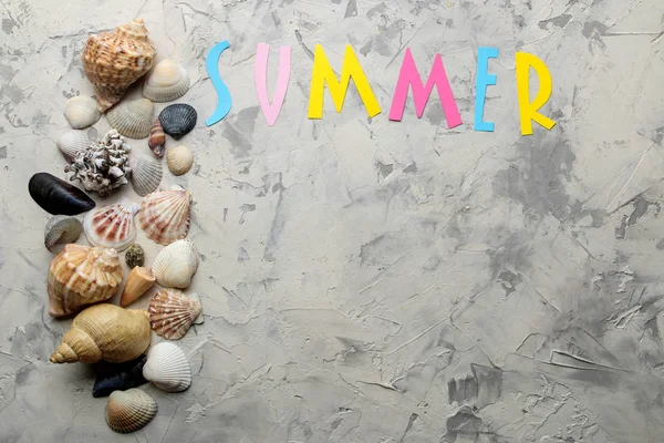 Inscription summer from paper of multi-colored letters and seashells and summer accessories on the sea sand. Summer. relaxation. vacation. top view