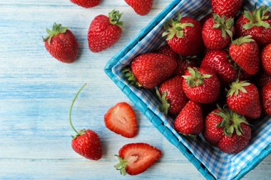 Olgun, lezzetli çilekler. Açık mavi ahşap bir masa üzerinde hasır sepet kırmızı çilek. üst görünüm