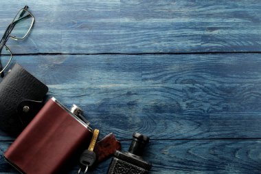 Erkek Accessories.men'ın tarzı. Gözlük, iş kart sahibi, puro, smartphone, dizüstü bilgisayar, kulaklık ve mavi ahşap arka plan çakmakta tabanca. Lay lay.