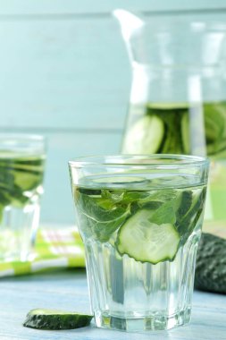 salatalık ile su. Mavi bir arka plan üzerinde bir cam beher salatalık ve nane ile ferahlatıcı diyet suyu. detoks içecek kavramı. yaz serinletici içecek.