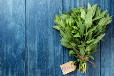 Nane. Yaprakları ve taze yeşil yabani nane dalları ve ahşap mavi bir masa üzerinde bir yazıt ile bir işaret. üst görünüm. metin için alan
