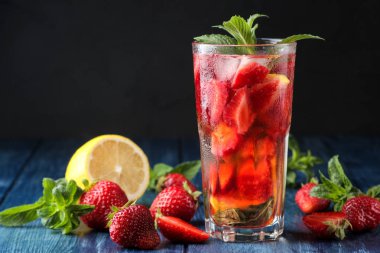 Çilek mojito. Mavi ahşap bir masa üzerinde bir bardak çilek, nane, limon ve buz ile Soğuk yaz mojito kokteyl. koyu bir arka plan üzerinde