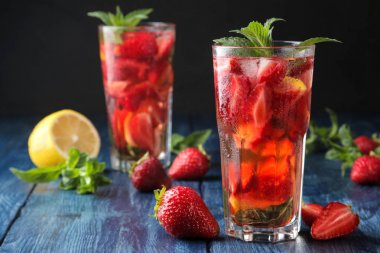 Çilek mojito. Mavi ahşap bir masa üzerinde bir bardak çilek, nane, limon ve buz ile Soğuk yaz mojito kokteyl. koyu bir arka plan üzerinde