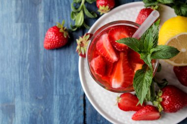 Çilek mojito. Mavi ahşap bir masa üzerinde bir bardak çilek, nane, limon ve buz ile Soğuk yaz mojito kokteyl. karanlık bir arka plan üzerinde. üst görünüm