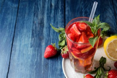 Çilek mojito. Mavi ahşap bir masa üzerinde bir bardak çilek, nane, limon ve buz ile Soğuk yaz mojito kokteyl. koyu bir arka plan üzerinde