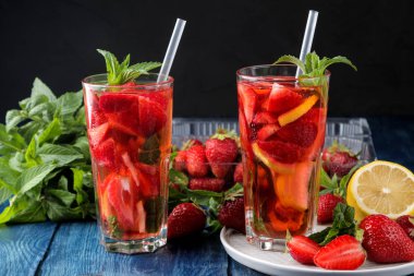 Çilek mojito. Mavi ahşap bir masa üzerinde bir bardak çilek, nane, limon ve buz ile Soğuk yaz mojito kokteyl. koyu bir arka plan üzerinde