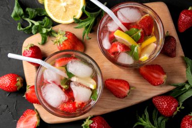 Çilek mojito. Siyah bir masa üzerinde bir bardak çilek, nane, limon ve buz ile Soğuk yaz mojito kokteyl. yaz serinletici içecek. üst görünüm