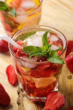 Çilek mojito. Doğal ahşap bir masa üzerinde bir bardak çilek, nane, limon ve buz ile soğuk yaz mojito kokteyl. Serinletici bir yaz içkisi. Close
