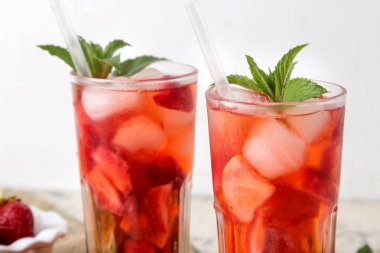 Çilek mojito. Doğal ahşap bir masa üzerinde bir bardak çilek, nane, limon ve buz ile soğuk yaz mojito kokteyl. Serinletici bir yaz içkisi. Close