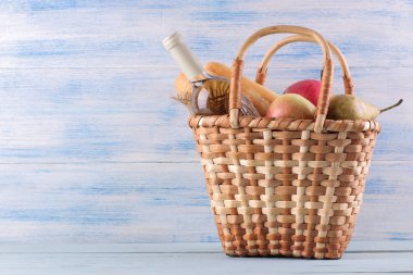 Mavi arka planda şarap meyvesi ve diğer ürünlerle piknik sepeti. Yaz dinlenme. Kamp. Doğada piknik.