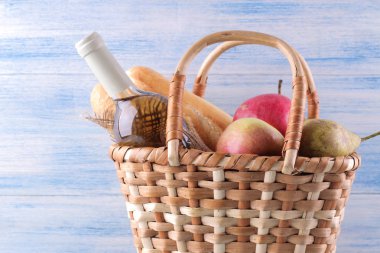 Mavi arka planda şarap meyvesi ve diğer ürünlerle piknik sepeti. Yaz dinlenme. Kamp. Doğada piknik.