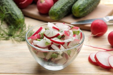 Doğal ahşap masada taze turp ve salatalık salata ve yeşillikler. Bahar sebzeleri salatası. salata yapmak için malzemeler.