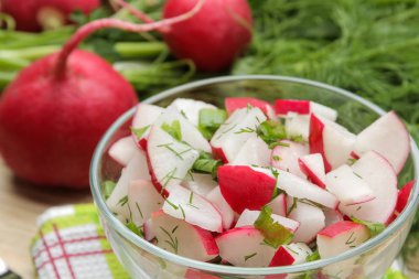 Doğal ahşap masada taze turp ve salatalık salata ve yeşillikler. Bahar sebzeleri salatası. salata yapmak için malzemeler.