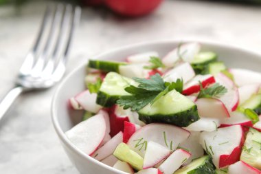 Hafif bir beton masada taze turp ve salatalık salata ve yeşillikler. Bahar sebzeleri salatası. salata yapmak için malzemeler.