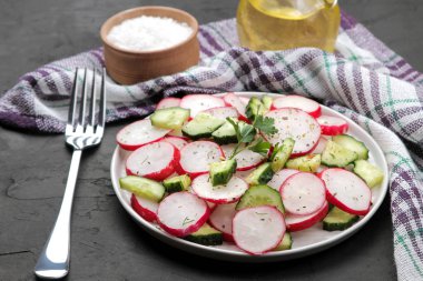 Siyah beton masada taze turp ve salatalık salata ve yeşillikler. Bahar sebzeleri salatası. salata yapmak için malzemeler. 