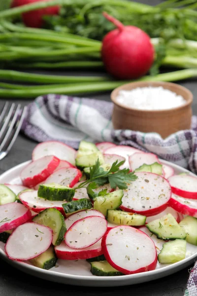 Fresh radish and cucumber salad and greens on a black concrete table. Salad of spring vegetables. ingredients for making salad.