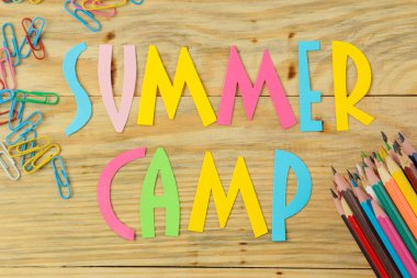 Doğal ahşap arka plan üzerinde çok renkli kağıt harfler ve renkli kalemler Metin Yaz Kampı. üst görünüm. düz yatıyordu