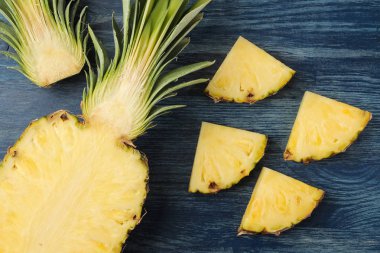Taze olgun ananas yarım ve mavi ahşap arka plan üzerinde ananas dilimleri. Yaz. Meyve. üst görünüm.