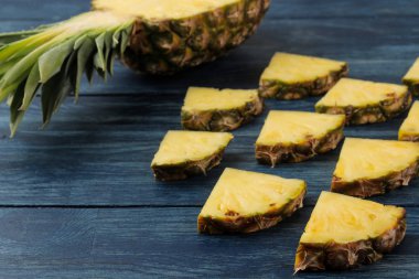 Taze olgun ananas yarım ve mavi ahşap arka plan üzerinde ananas dilimleri. Yaz. Meyve.