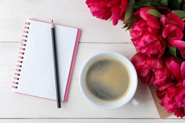Güzel parlak pembe çiçekler şakayık ve beyaz ahşap arka plan üzerinde bir fincan kahve ile bir dizüstü bilgisayar. üst görünüm.