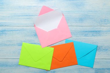 Mavi ahşap masadaki metin için boş renkli zarflar. üst görünüm