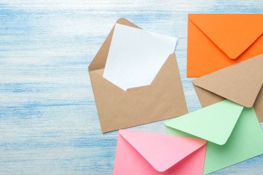 Mavi ahşap masadaki metin için boş renkli zarflar. üst görünüm