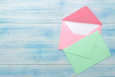 Mavi ahşap masadaki metin için boş renkli zarflar. üst görünüm