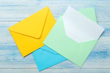 Mavi ahşap masadaki metin için boş renkli zarflar. üst görünüm