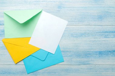 Mavi ahşap masadaki metin için boş renkli zarflar. üst görünüm