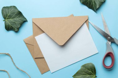 Parlak trendy açık mavi arka plan üzerinde metin ve yeşil yaprakları için zanaat zarf ve form. üst görünüm