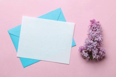 Metin için boş mavi zarf ve parlak trendy pembe arka plan üzerinde leylak bir dalı. üst görünüm