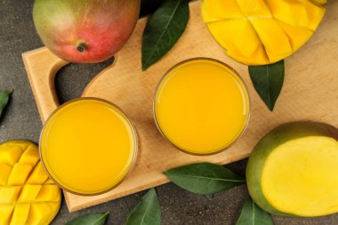 Olgun taze mango meyve ve dilimler ve mango suyu karanlık bir arka plan üzerinde bir bardak. tropikal meyve. üst görünüm