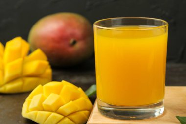 Olgun taze mango meyve ve dilimler ve mango suyu karanlık bir arka plan üzerinde bir bardak. tropikal meyve.
