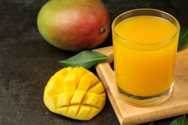 Olgun taze mango meyve ve dilimler ve mango suyu karanlık bir arka plan üzerinde bir bardak. tropikal meyve.
