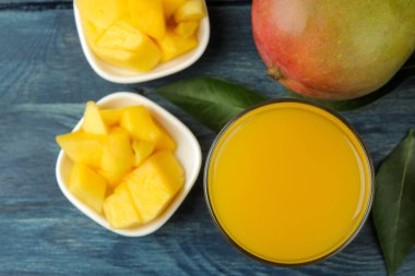 Olgun taze mango meyve ve dilimler ve mango suyu mavi ahşap bir masa üzerinde bir bardak. tropikal meyve. üst görünüm