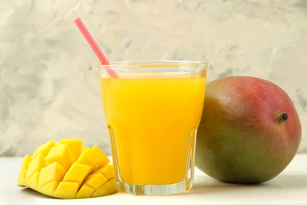 Ripe fresh mango fruit and mango juice in a glass on a light background. tropical fruit