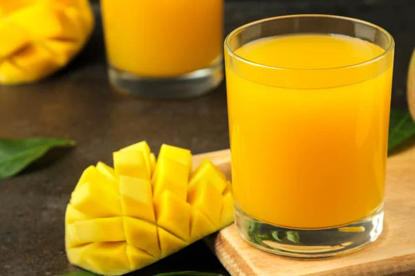 Ripe fresh mango fruit and slices and mango juice in a glass on a dark background. tropical fruit.