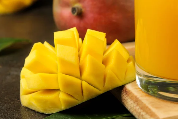 Ripe fresh mango fruit and slices and mango juice in a glass on a dark background. tropical fruit. close-up