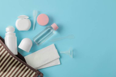 Açık mavi bir arka plan üzerinde bir kozmetik çantası seyahat için kozmetik ve kişisel bakım ürünleri bir dizi. üst görünüm. seyahat kozmetik