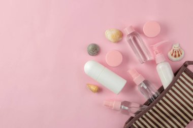 Açık pembe bir arka plan üzerinde bir kozmetik çantası seyahat için kozmetik ve kişisel bakım ürünleri bir dizi. üst görünüm. seyahat kozmetik
